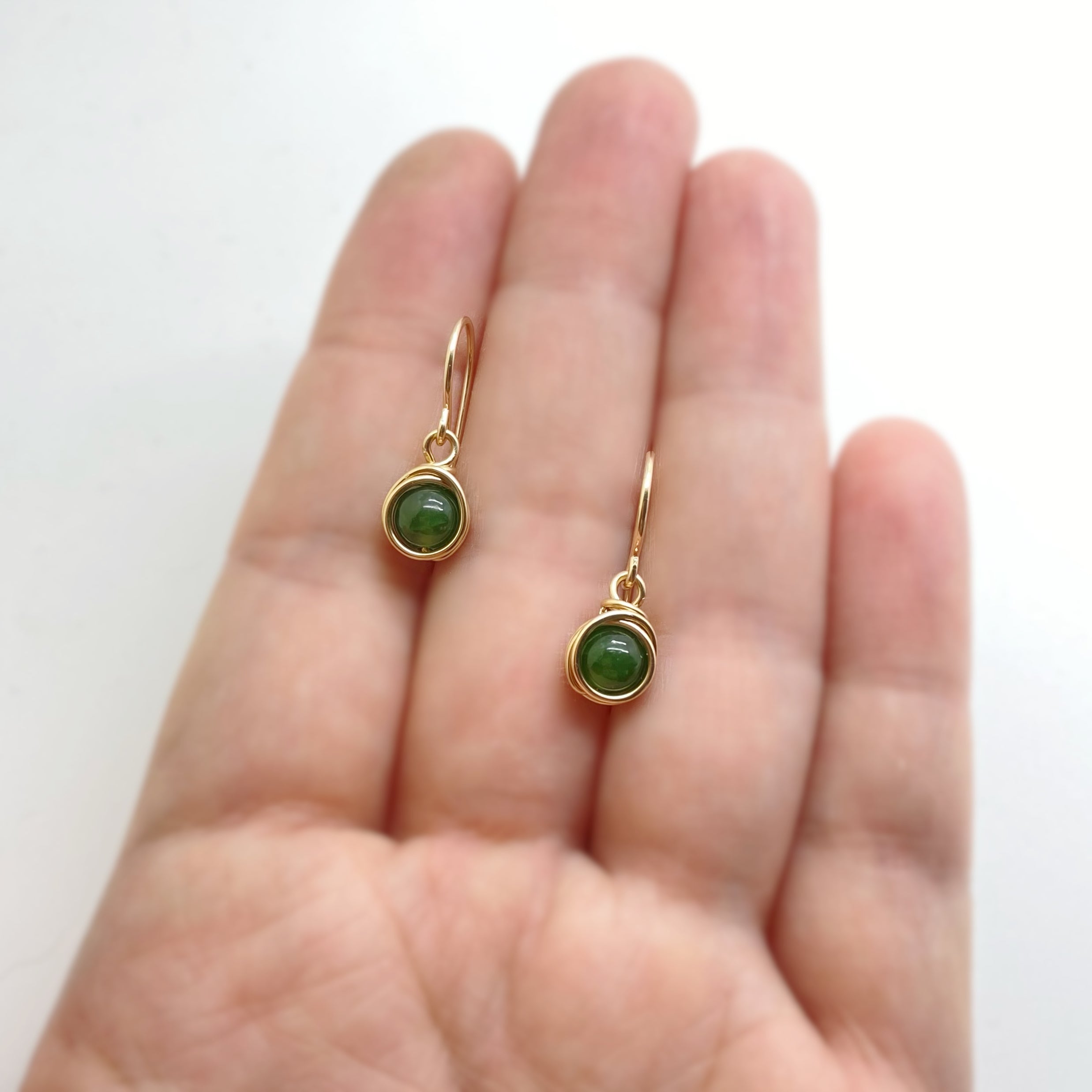 14k gold filled oorbellen met nefriet jade die op mijn hand liggen om de afmeting duidelijk te tonen
