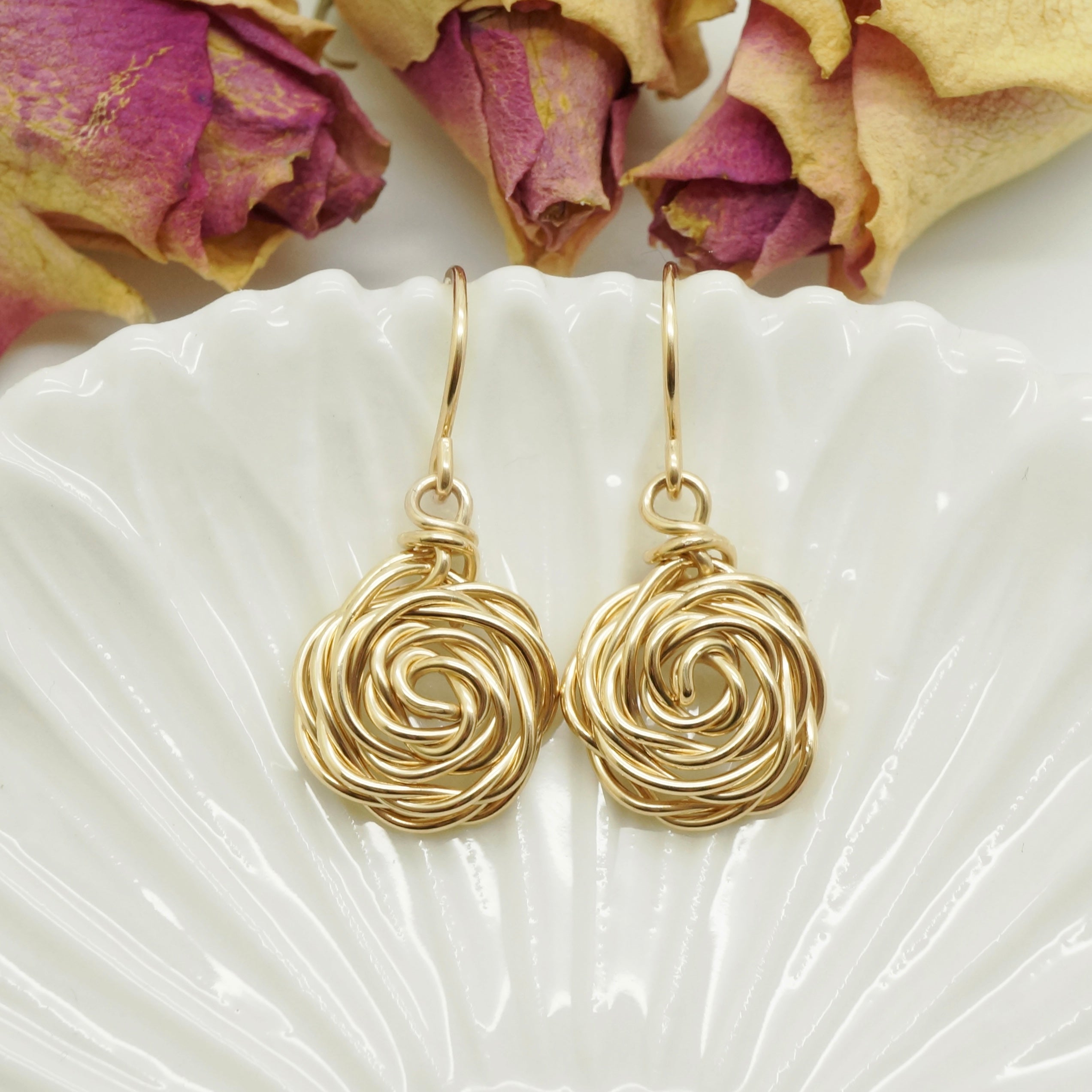 Close-up van handgemaakte 14k gold-filled oorbellen met roosmotief van Atelier Blaauw