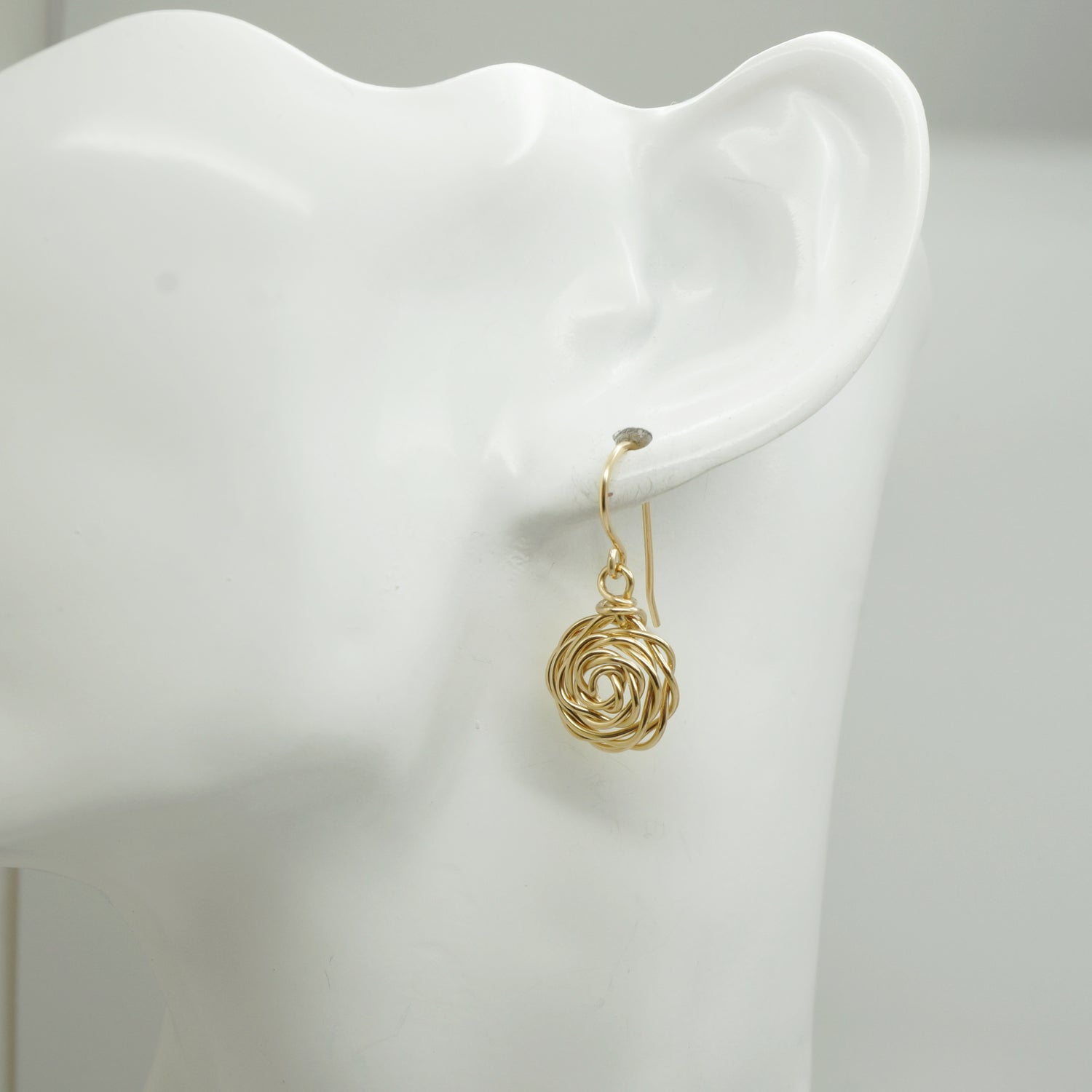14k Gold-Filled Roos Oorbellen gedragen door witte mannequin – handgemaakte oorbellen met bloemdesign in elegant gouden draadwerk, goed zichtbaar in het oor.