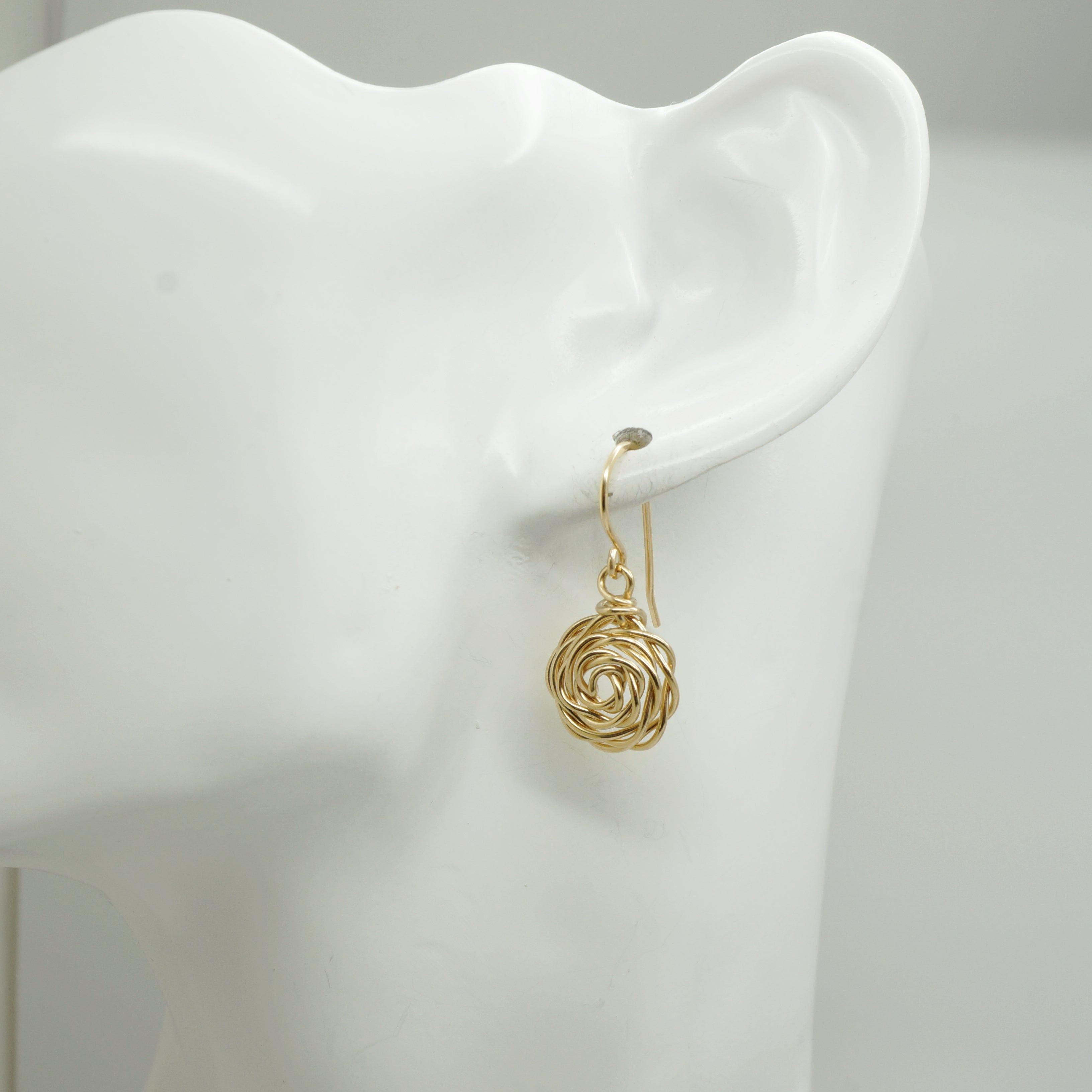 14k Gold-Filled Roos Oorbellen gedragen door witte mannequin – handgemaakte oorbellen met bloemdesign in elegant gouden draadwerk, goed zichtbaar in het oor.