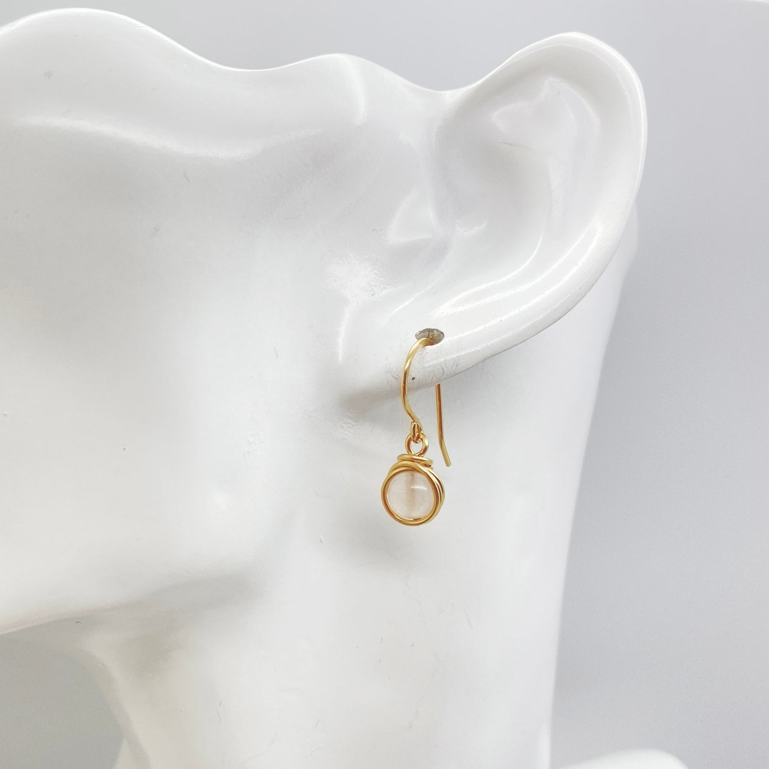 Model draagt 14K gold filled oorbellen met rozenkwarts, elegant bij elke gelegenheid.