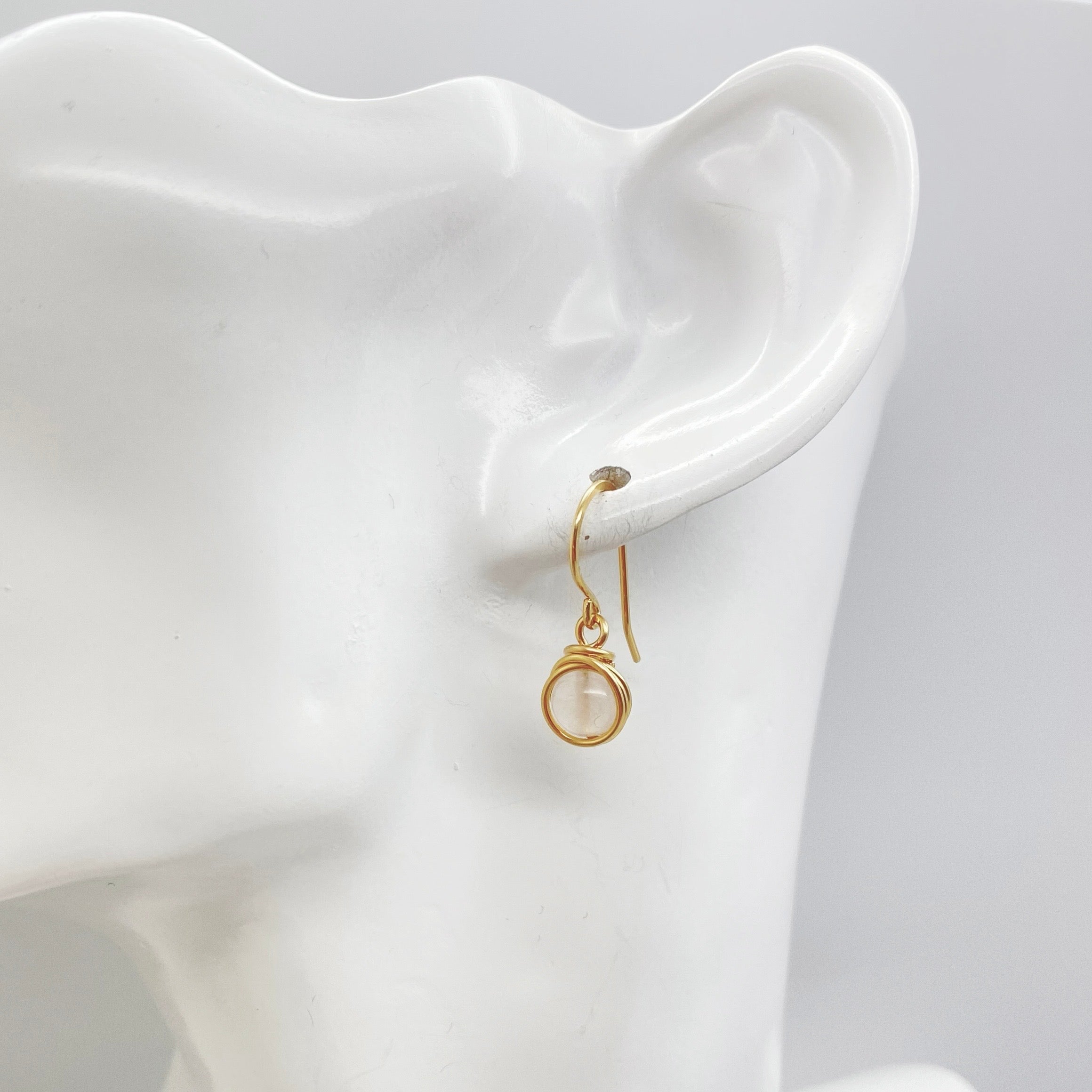 Model draagt 14K gold filled oorbellen met rozenkwarts, elegant bij elke gelegenheid.