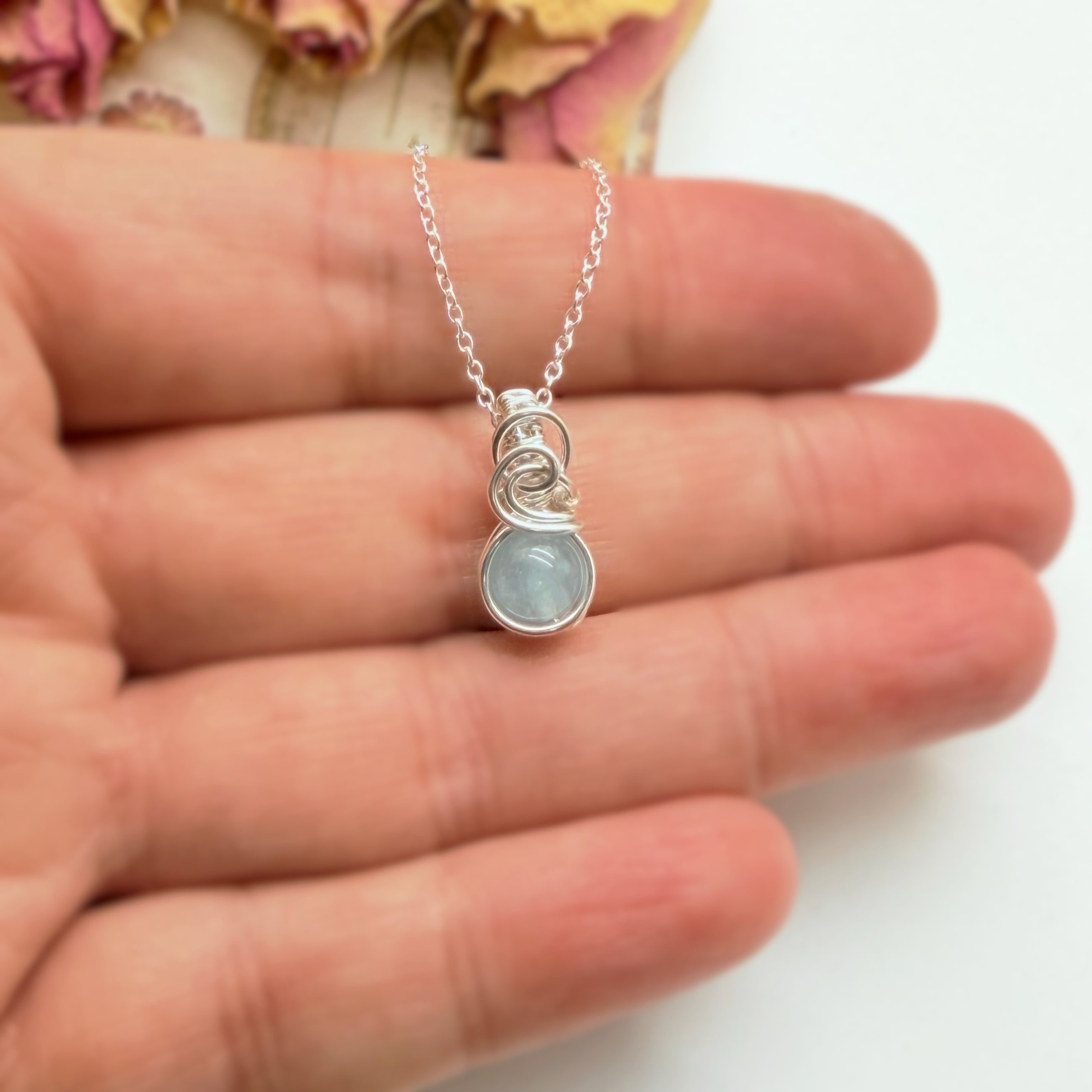 Klein handgemaakt aquamarijn hangertje van zilver getoond op de hand