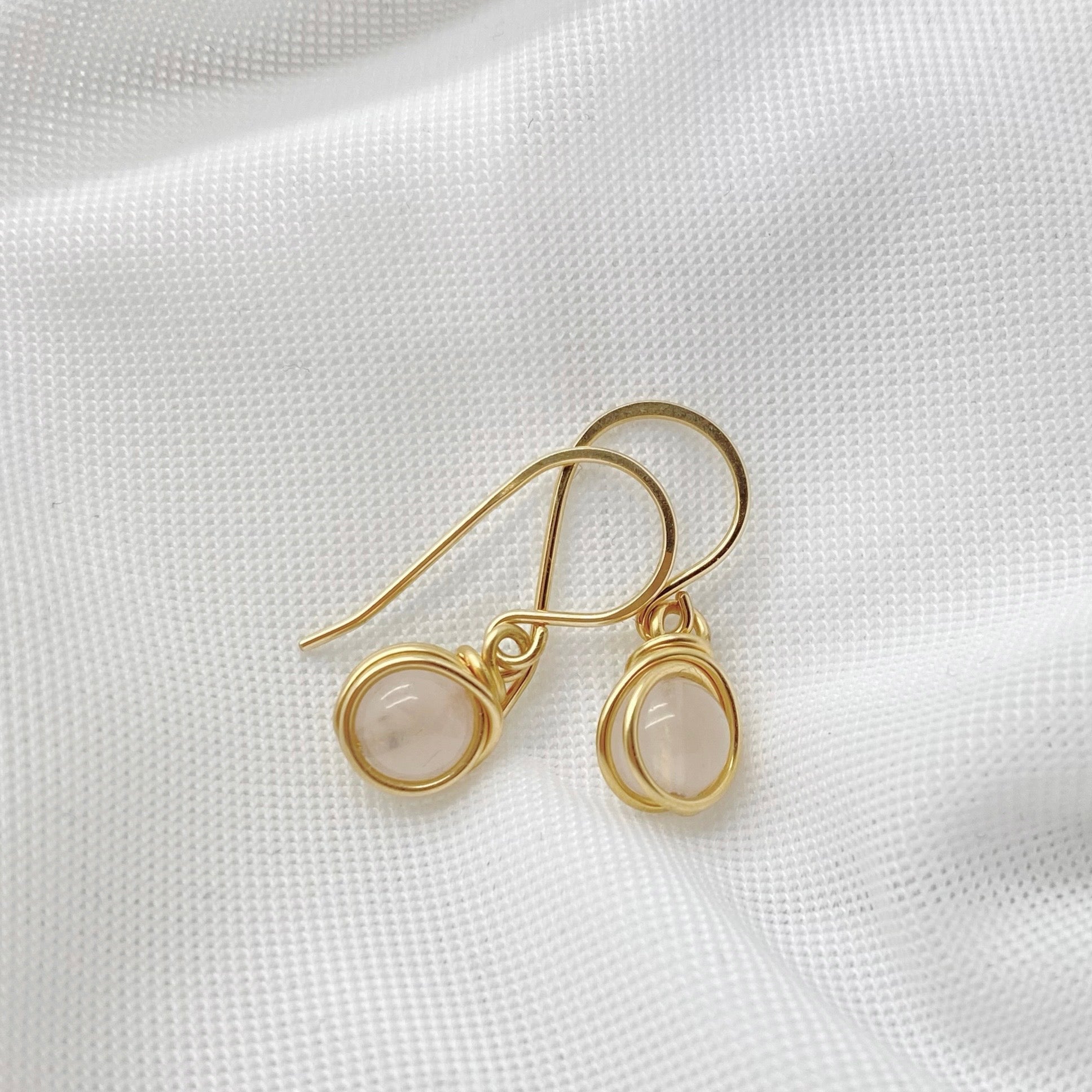 Bovenaanzicht van elegante 14K gold filled oorbellen met lichtroze rozenkwarts stenen.
