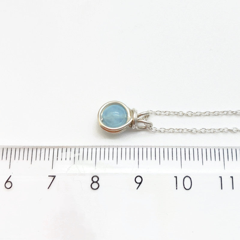 Zilveren collier met aquamarijn hanger naast een liniaal, toont de afmeting van de handgemaakte hanger.
