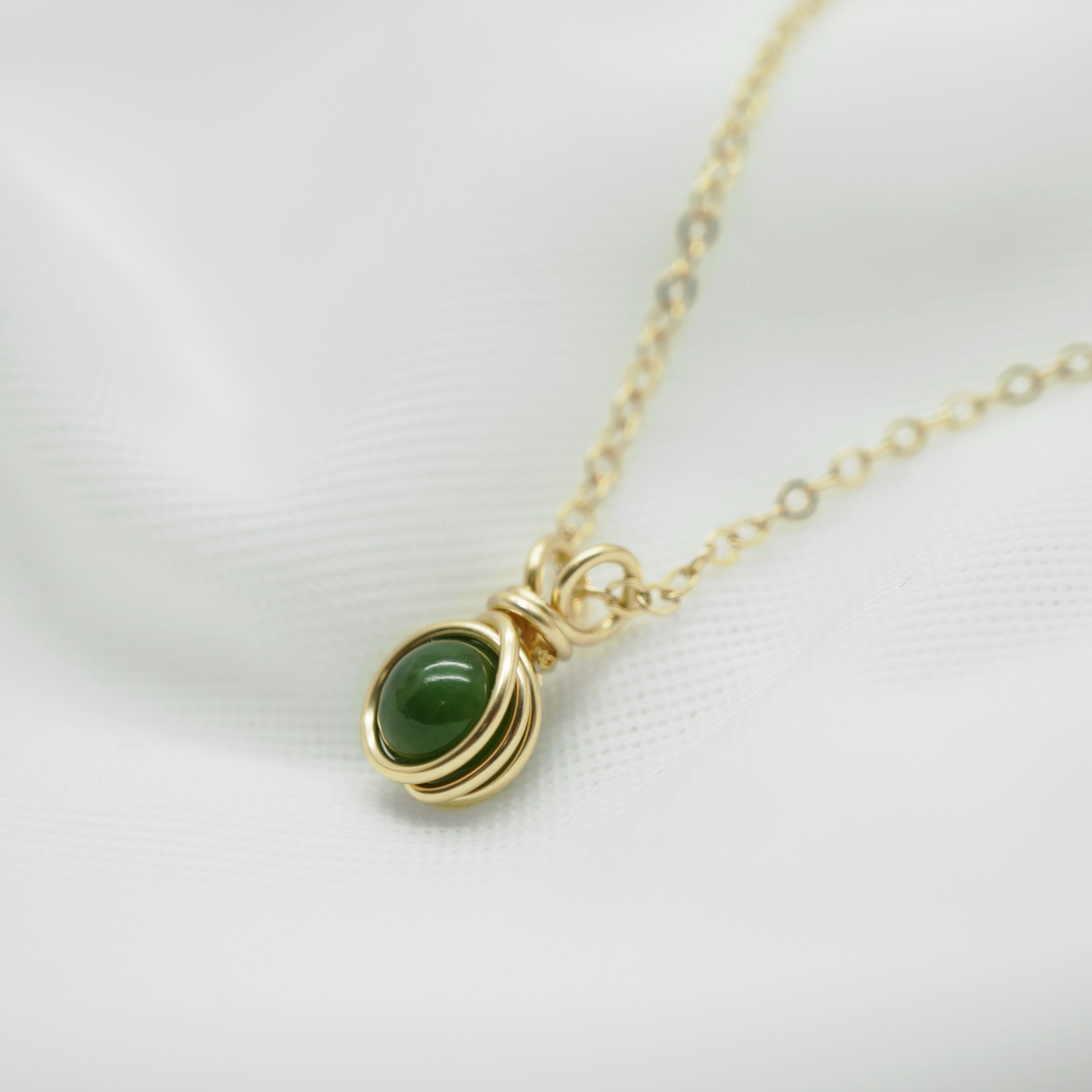 Zijaanzicht van draadgewikkelde hanger met nefriet jade in 14k gold filled draad.