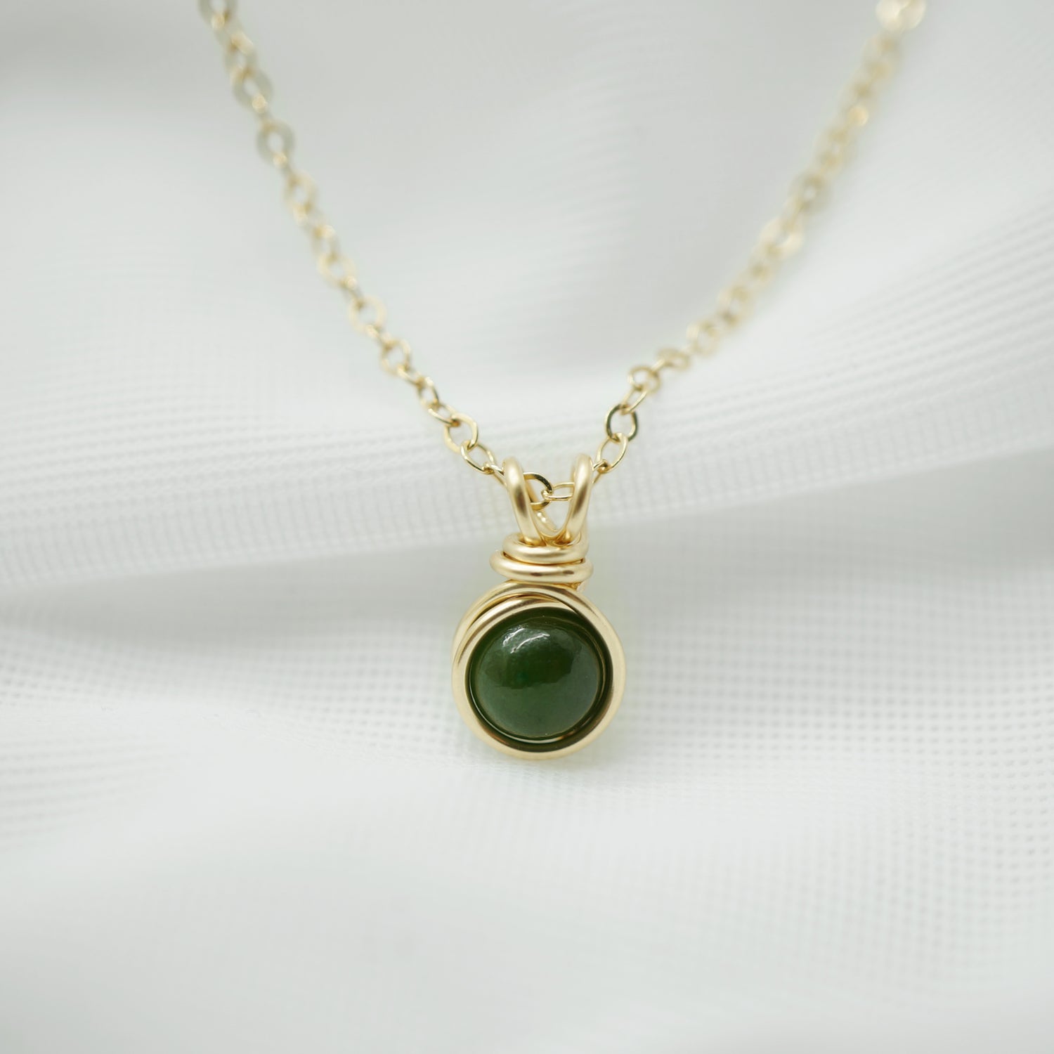 Detail van de hanger in 14k gold filled draad met gladde nefriet jade edelsteen.