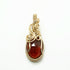 Close-up van handgemaakte hanger met oranjebruine spessartien granaat in 14k gold filled wire wrap.