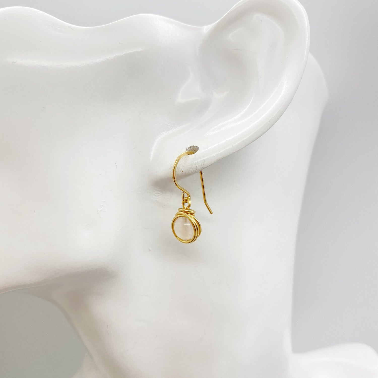 Zijaanzicht van de oorbel met lichtroze rozenkwarts en handgewikkelde gold filled draad.