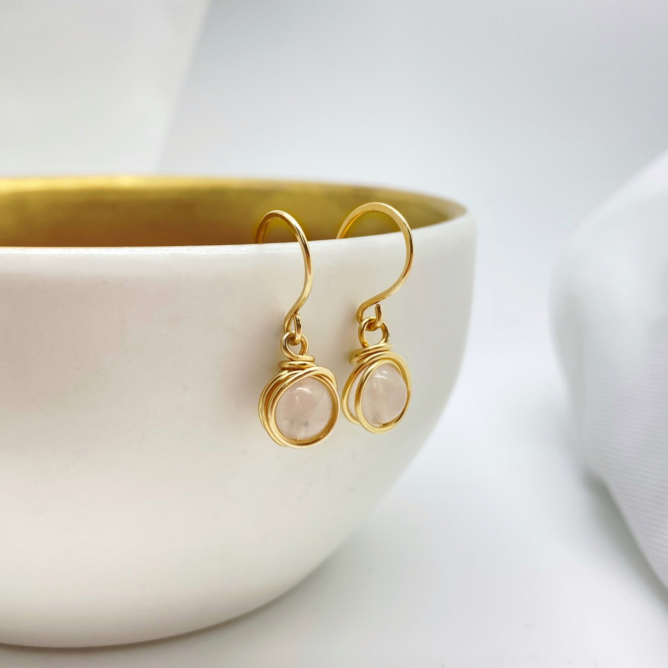 14K gold filled oorbellen met rozenkwarts hangend aan een decoratief potje, stijlvolle presentatie van handgemaakte sieraden.