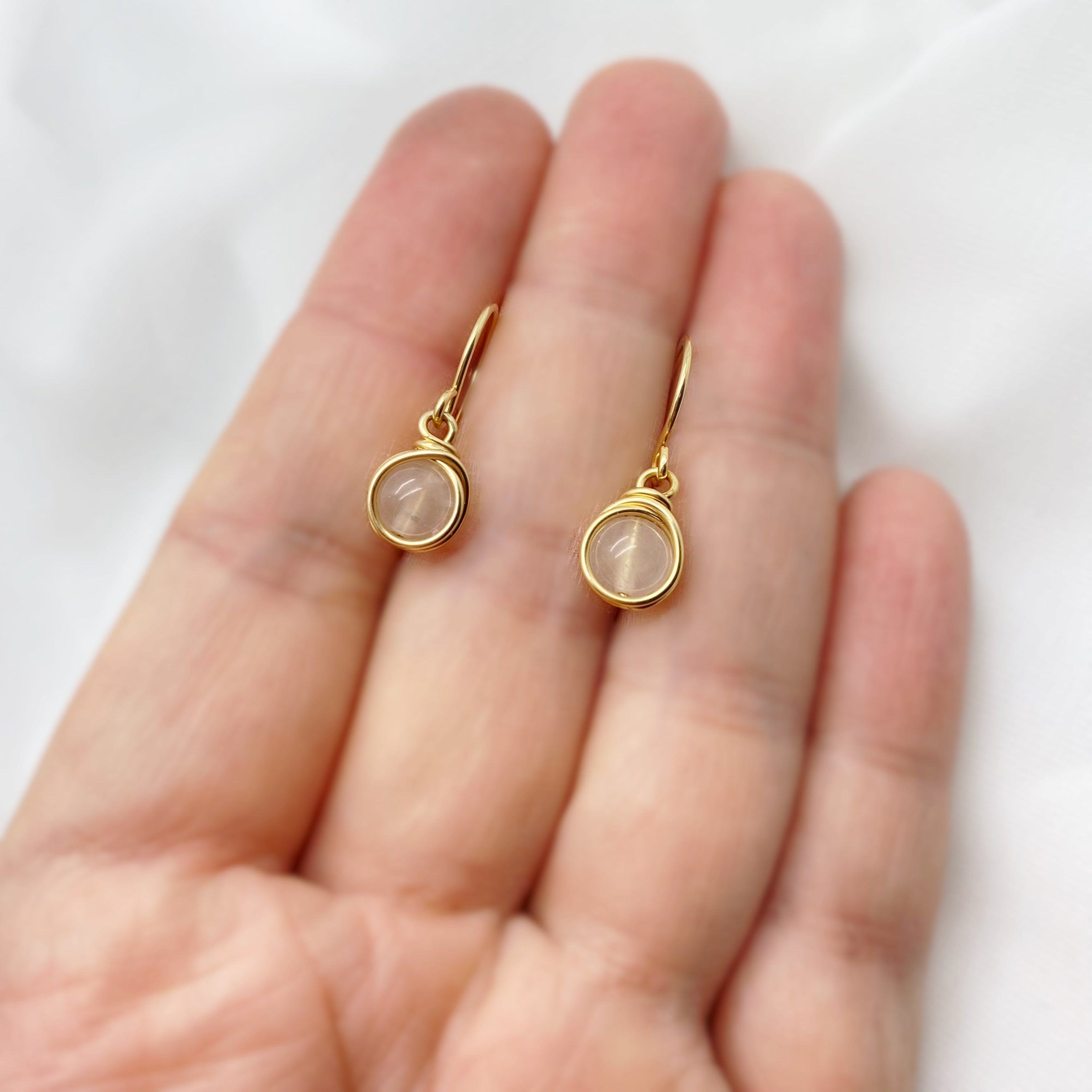 14K gold filled oorbellen met rozenkwarts rustend op een hand, toont het formaat van de sieraden in verhouding tot de hand.