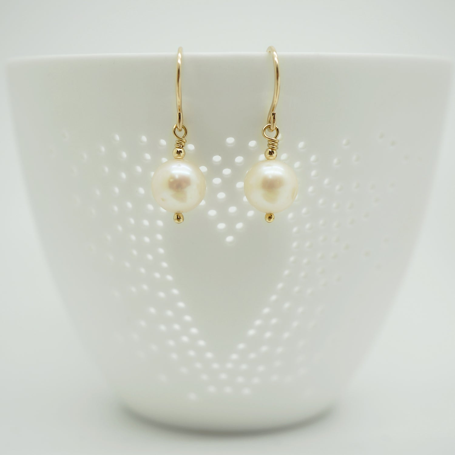 Sfeervolle presentatie van klassieke gold filled oorbellen met witte parels, geschikt voor elke gelegenheid.
