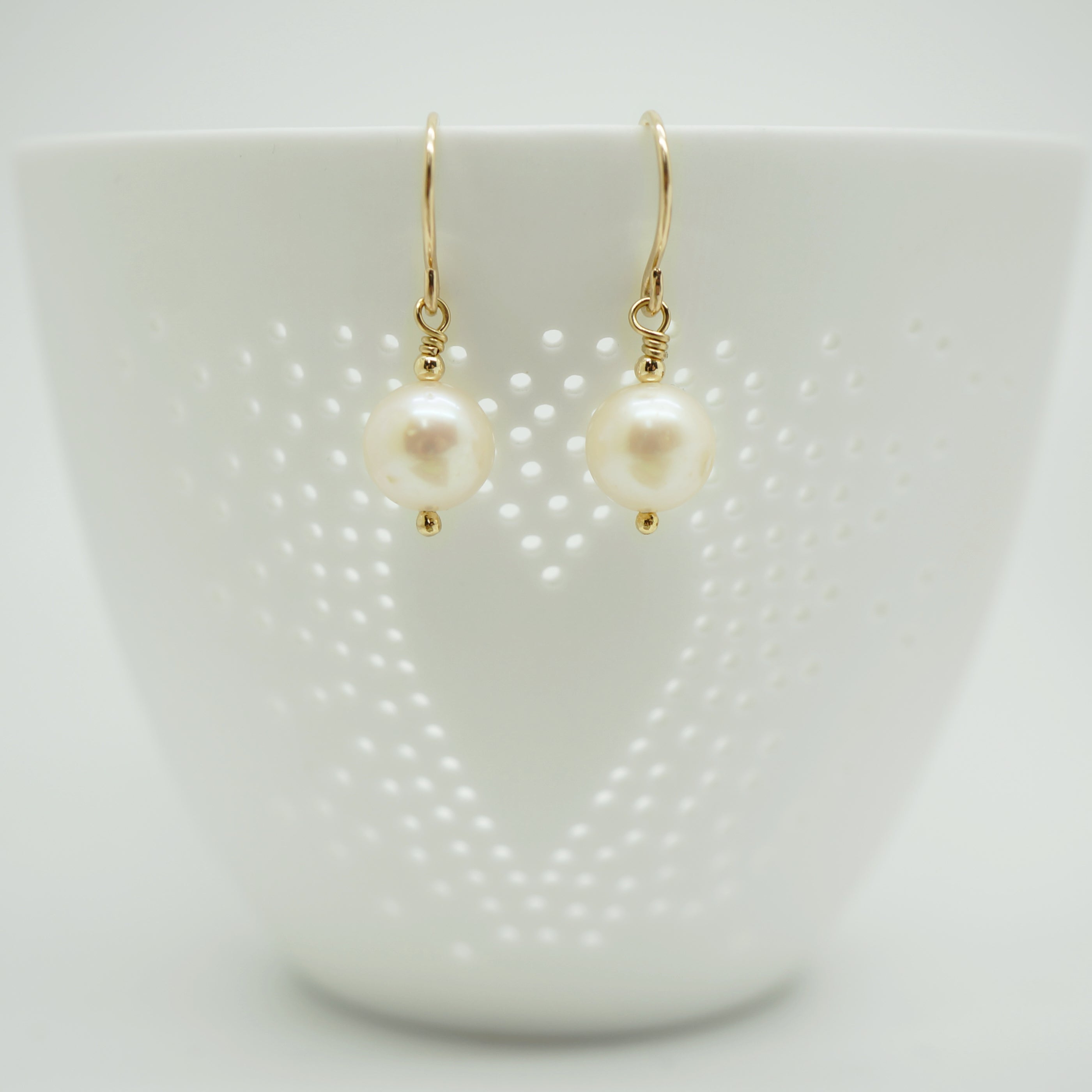 Sfeervolle presentatie van klassieke gold filled oorbellen met witte parels, geschikt voor elke gelegenheid.