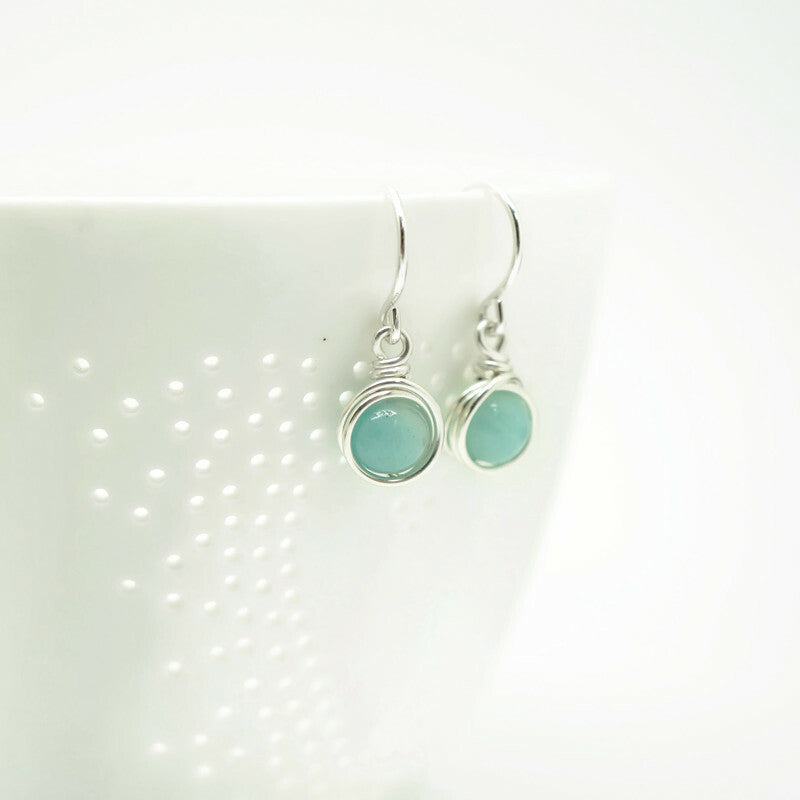 Amazoniet oorbellen in sterling zilver gepresenteerd op een witte porseleinen ondergrond, Atelier Blaauw.