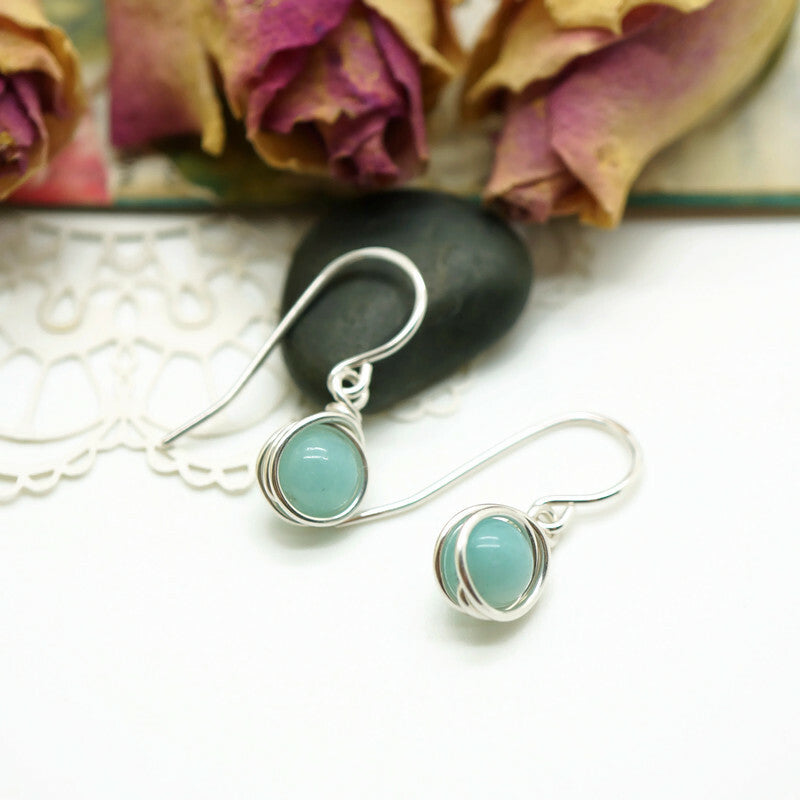 Zilveren oorbellen met Amazoniet in romantische setting met rozen, handgemaakt door Atelier Blaauw.
