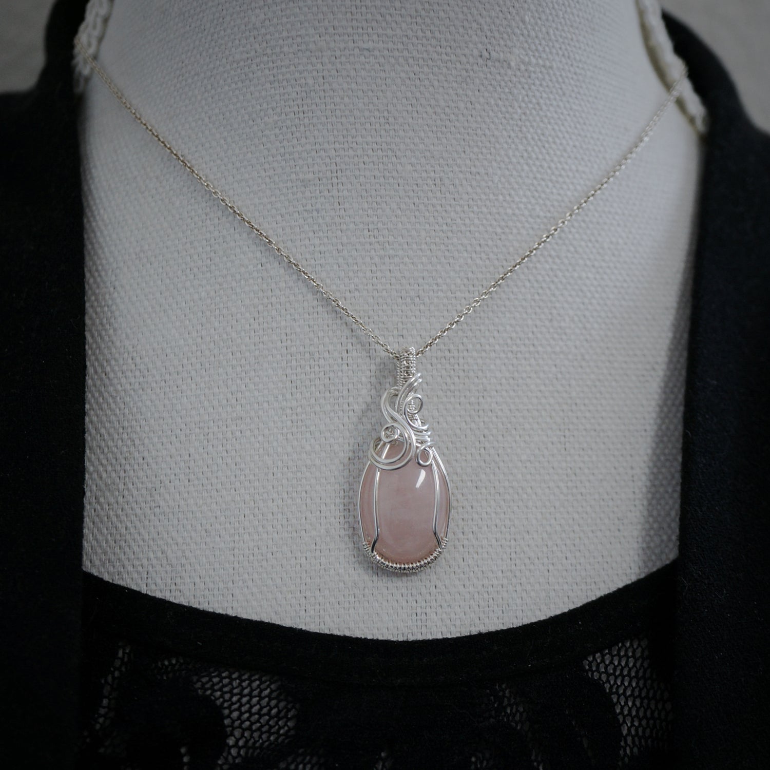 Zilveren hanger met rozenkwarts gedragen aan een ketting, verfijnd en vrouwelijk.