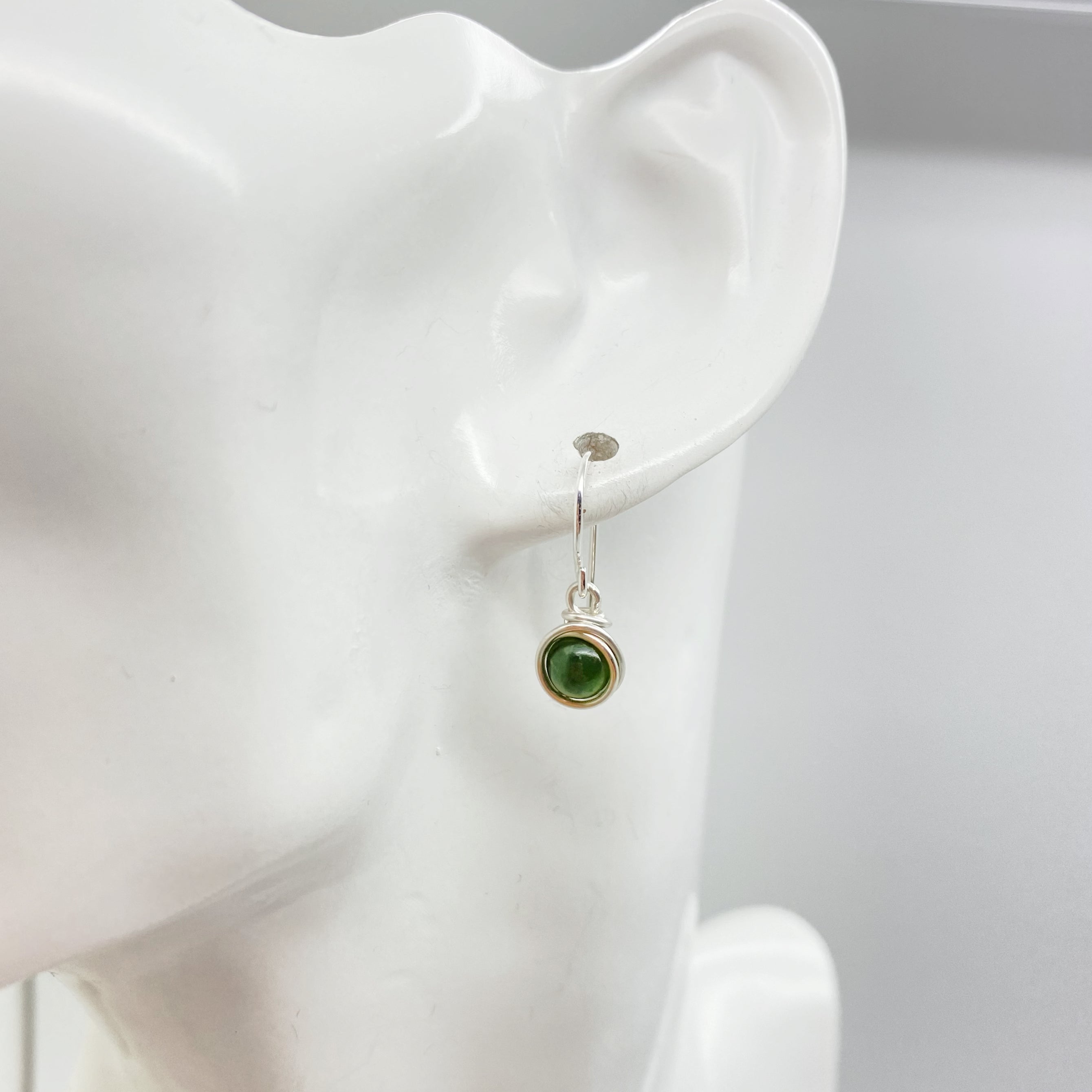 Zilveren oorbel met nefriet jade gezien van voren tijdens het dragen
