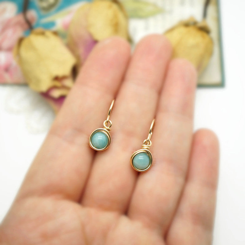 Handgemaakte 14k gold filled oorbellen met Amazoniet, gepresenteerd op een hand.