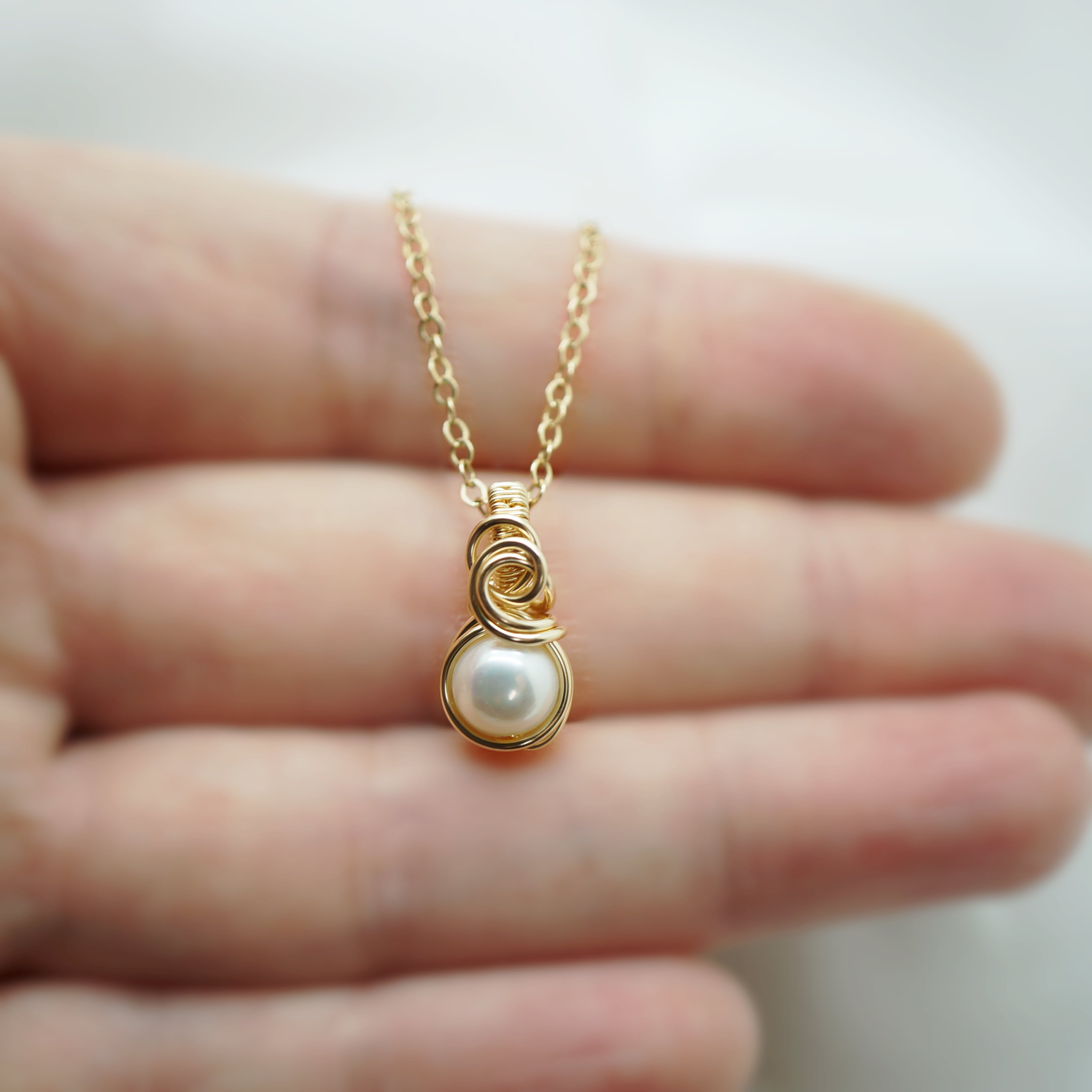 Close up van gold filled draadwerk rond een zachte creme parel