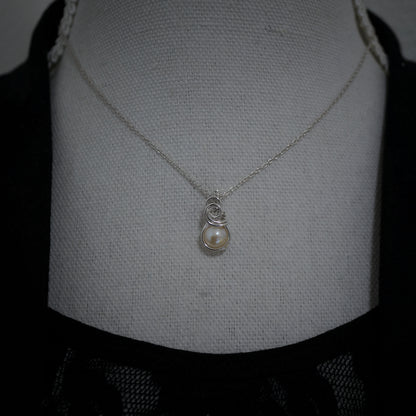 Zilveren wire wrap hanger met parel gedragen aan collier, minimalistische stijl