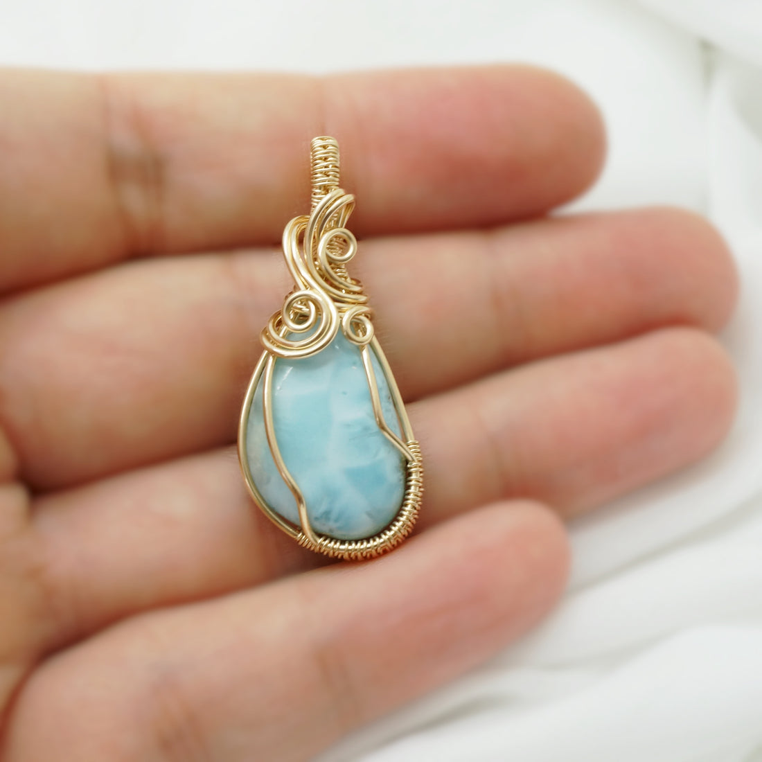 Handgemaakte larimar hanger met 14k gold filled draad, gepresenteerd op een hand.