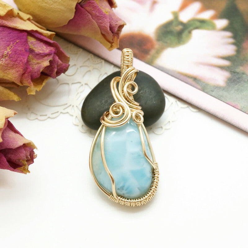 Sfeervolle productfoto van een handgemaakte 14k gold filled larimar hanger met droogbloemen.