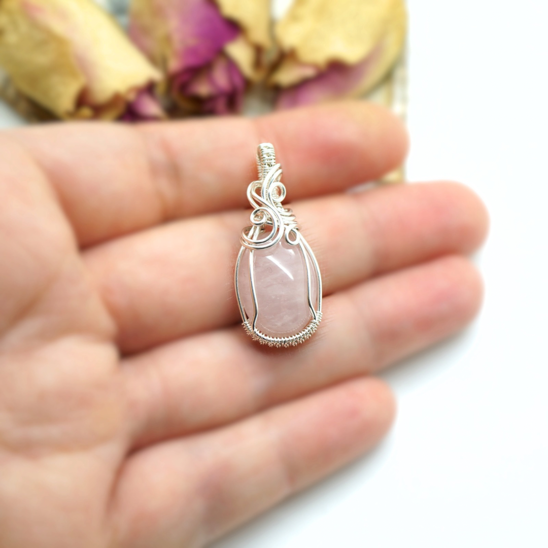 Close-up van de rozenkwarts edelsteen en het draadwerk in sterling zilveren hanger.