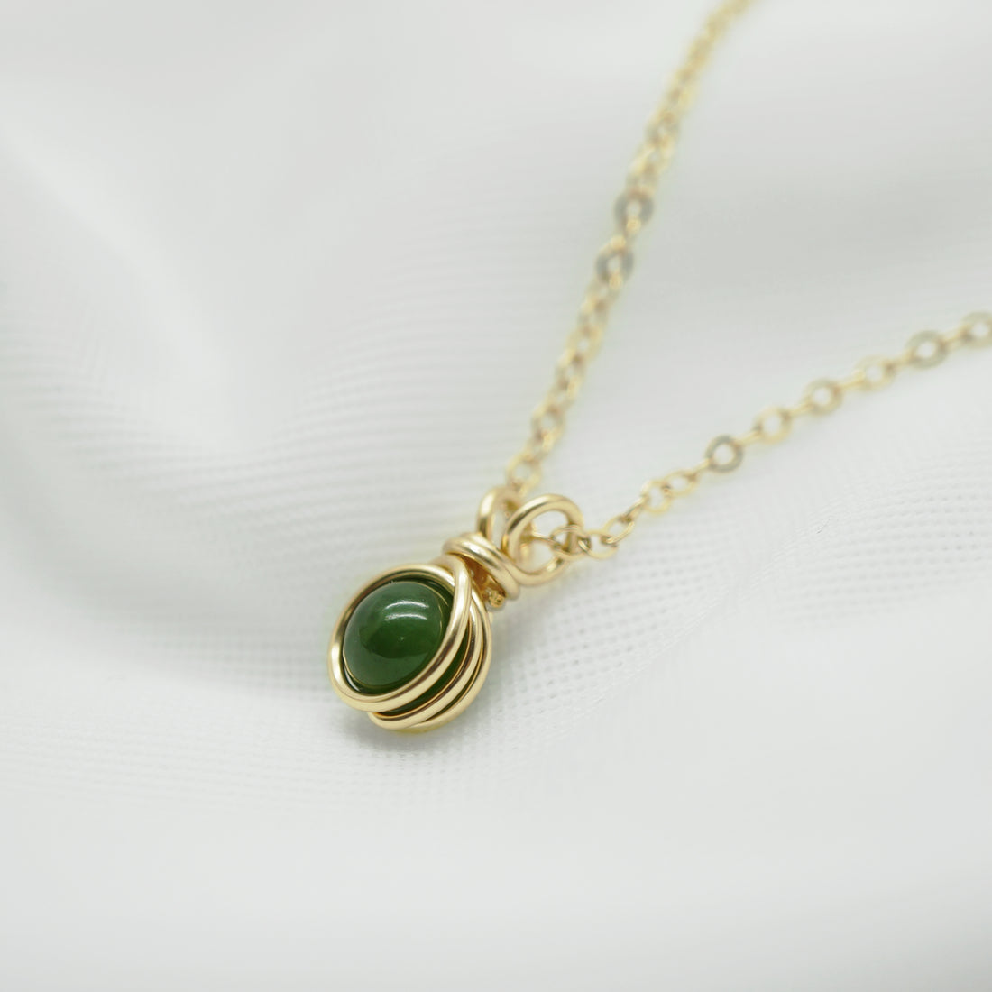 Zijaanzicht van draadgewikkelde hanger met nefriet jade in 14k gold filled draad.