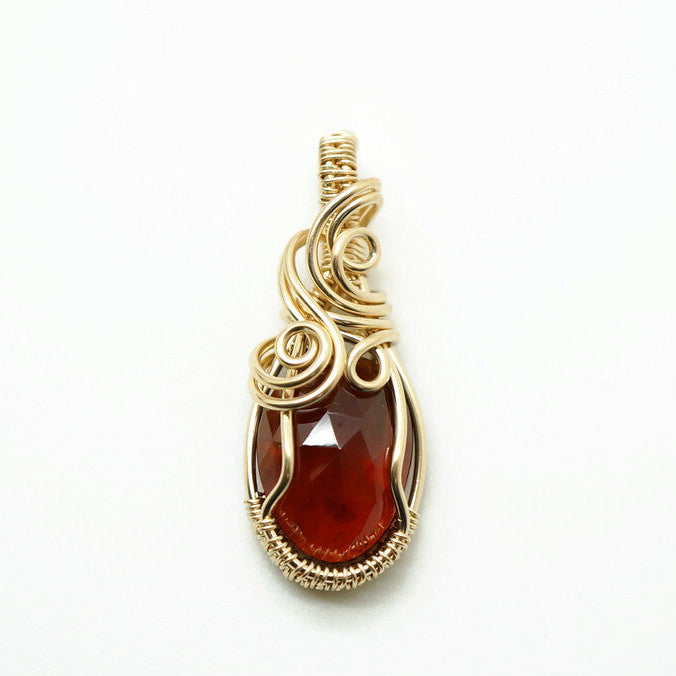 Close-up van handgemaakte hanger met oranjebruine spessartien granaat in 14k gold filled wire wrap.