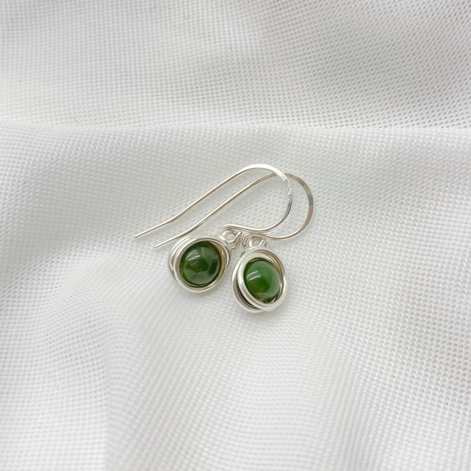 Detailfoto van zilveren oorbellen met nefriet jade en gladde zetting