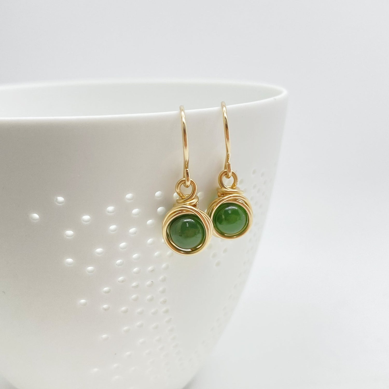 Oorbellen met nefriet jade hangend aan een klein potje voor een sfeervolle presentatie