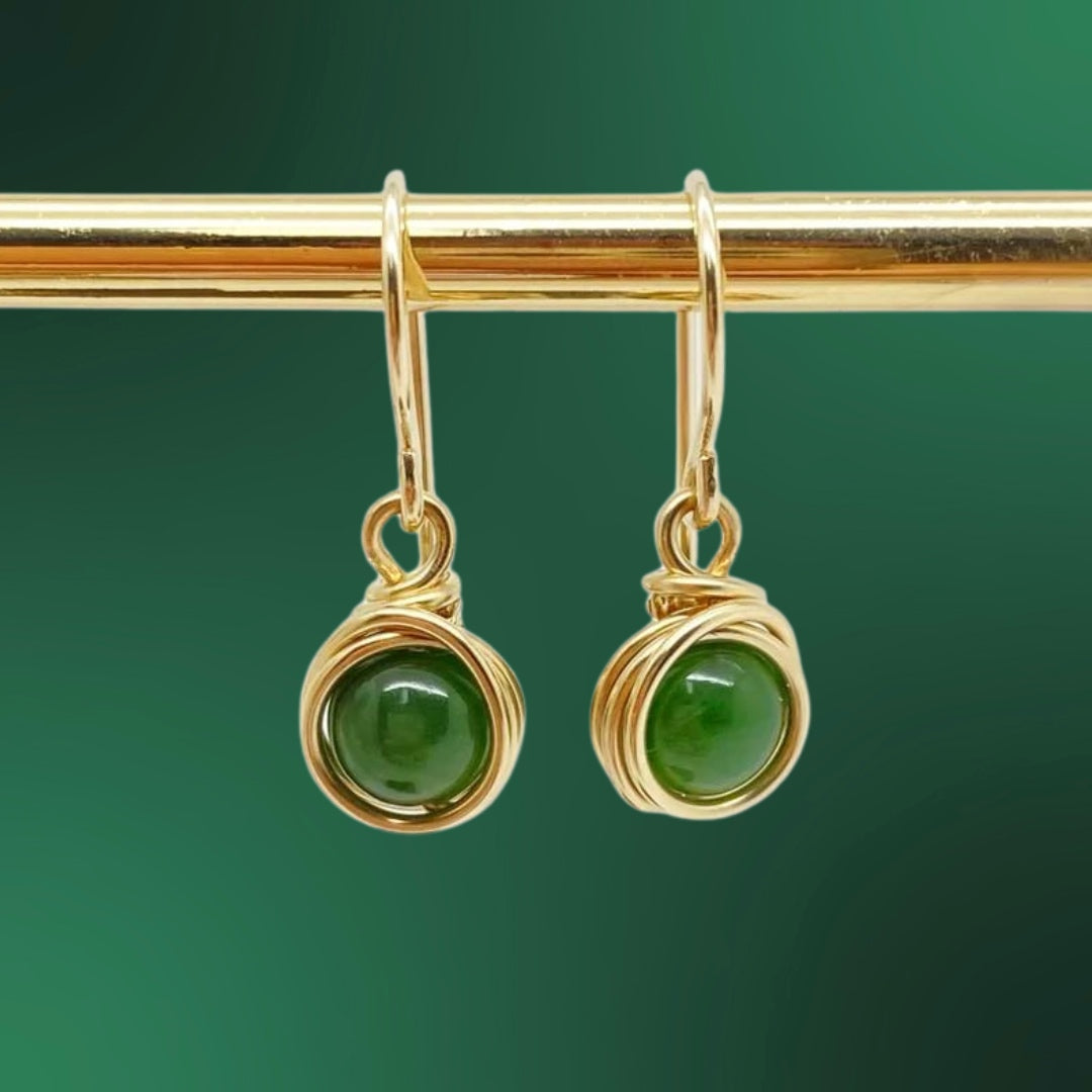 Oorbellen met nefriet jade gefotografeerd tegen een groene achtergrond voor een rustige natuurlijke sfeer