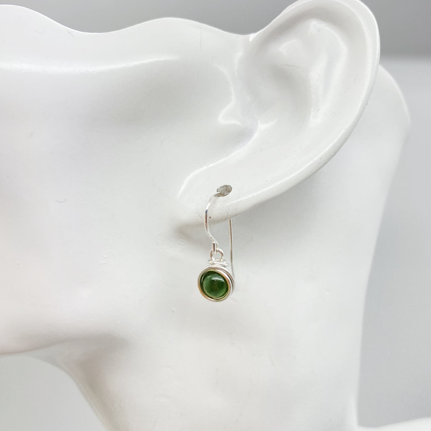 Zilveren oorbel met nefriet jade gedragen in het oor subtiel en elegant