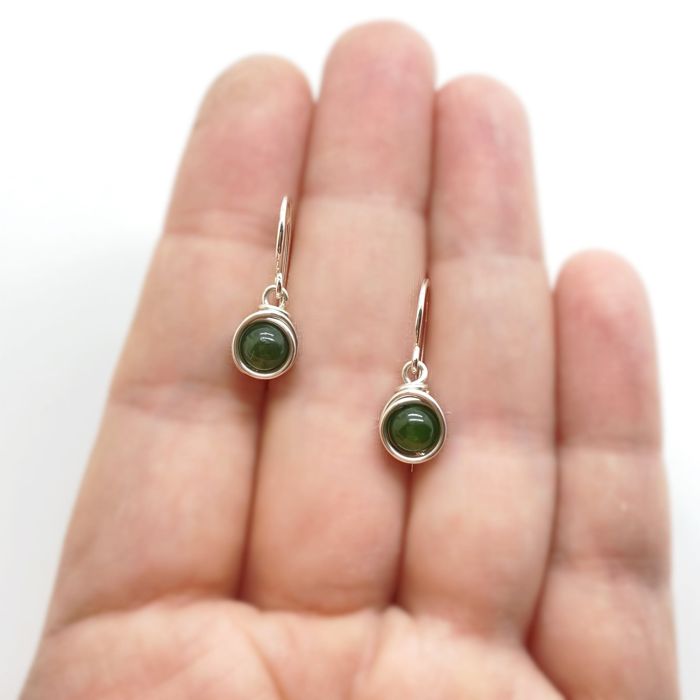 Zilveren oorbellen met nefriet jade getoond op hand voor formaat en draaggrootte